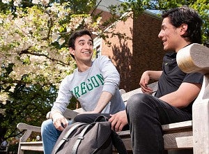 Two students sitting on bench in front of Knight Library