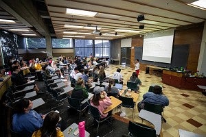 Professor teaches students in front of projector screen
