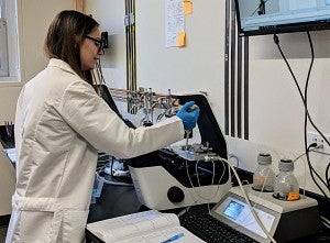 A scientist fills a vial in a machine
