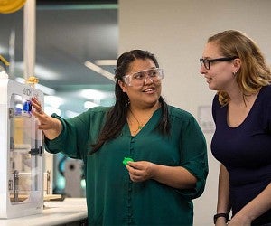 Two PHd students working with 3D printer