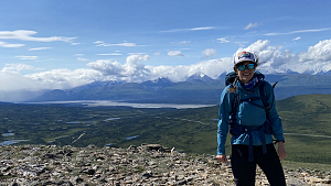 Woman stands in front of snowy mountains in the distance.