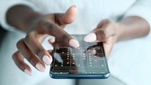Hands playing sudoku on a phone.