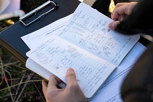 A student holds a journal with plant drawings