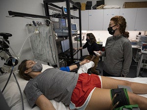 person lying on exam table with equipment on knee, with other people monitoring