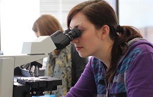 student looking into microscope