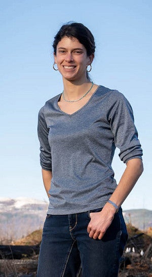 woman smiling in front of snowcovered distant mountains