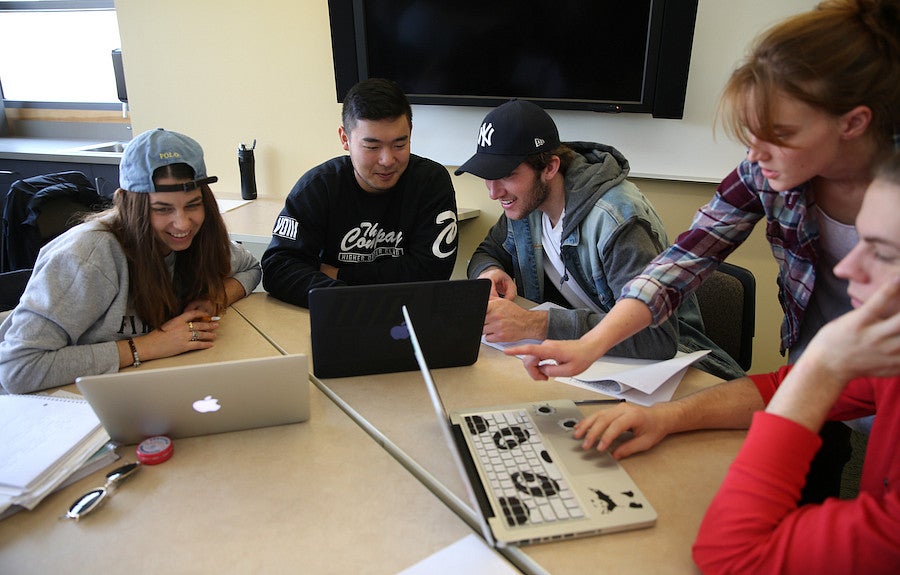 students at table with laptops talking