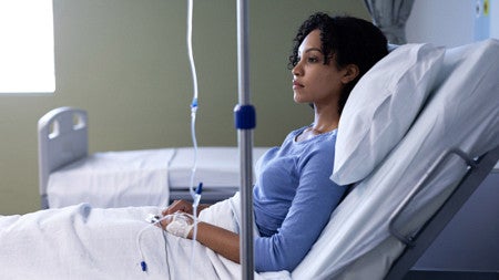 A black woman sits in a hospital bed 