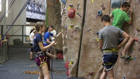 Students climb a rock wall 