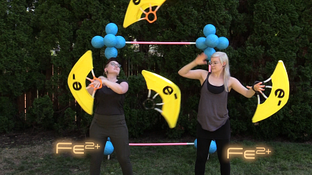 two people dancing with props resembling atoms and electrons