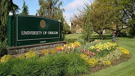 student walks by University of Oregon sign