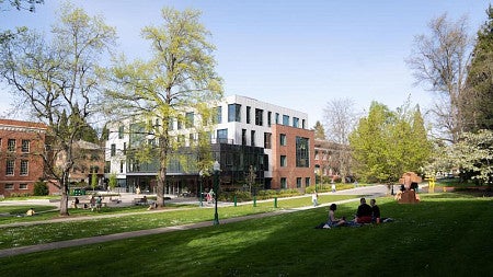 exterior shot of Tykeson hall and lawn with people sitting on grass in springtime
