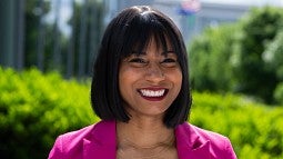 Headshot of a woman in a pink blazer smiling at the camera