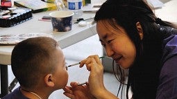 Nayeon Kim paints a young boys face