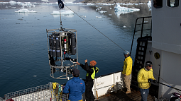 Researchers studying a fjord in Greenland prepare to place monitoring equipment in the water.