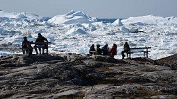 People sit in front of an iceberg 
