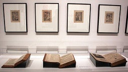 museum exhibit with framed works and books in glass case