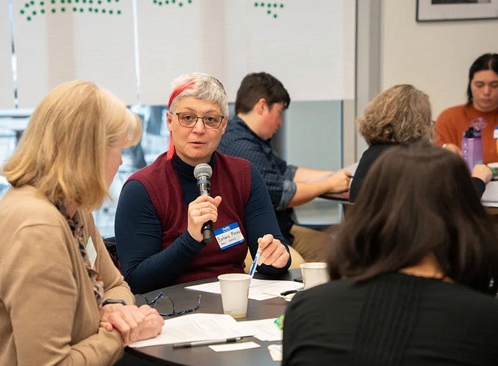 Person talking into a microphone seated at table