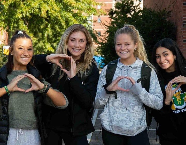 Undergraduate students posing for camera making hand signals