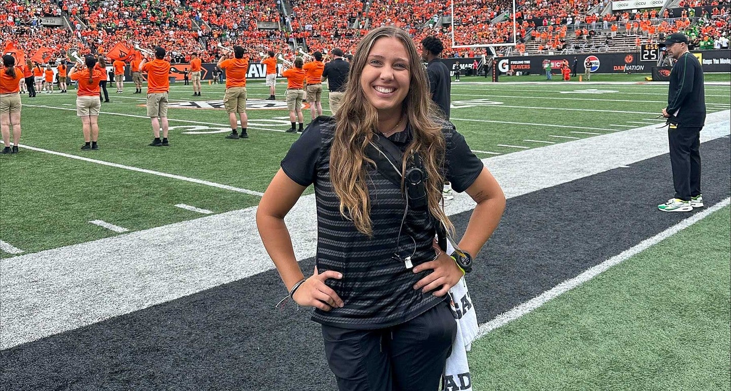 a student stands on the football sidelines