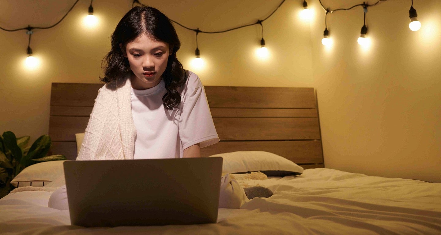 a person on a bed reading a computer