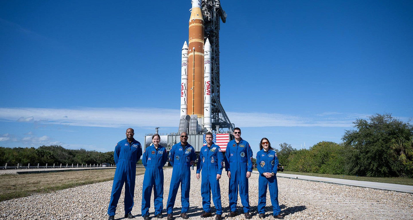 people standing in front of a NASA rocket