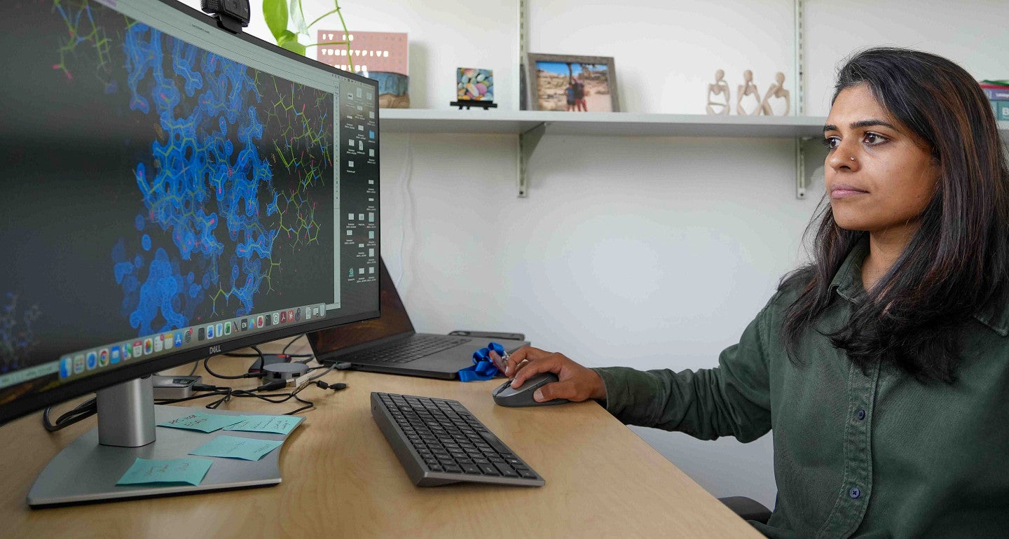 a person sitting at a desk looking at a colorful image on a computer screen
