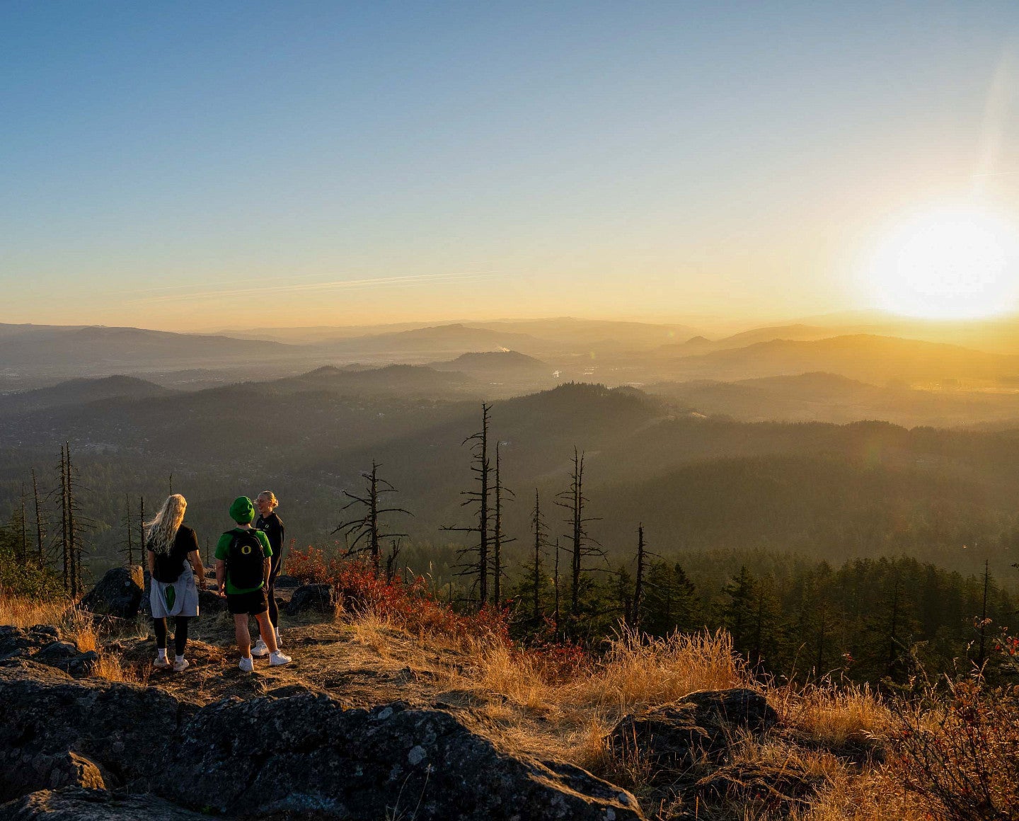people standing on top of a mountain with the sunset in the background