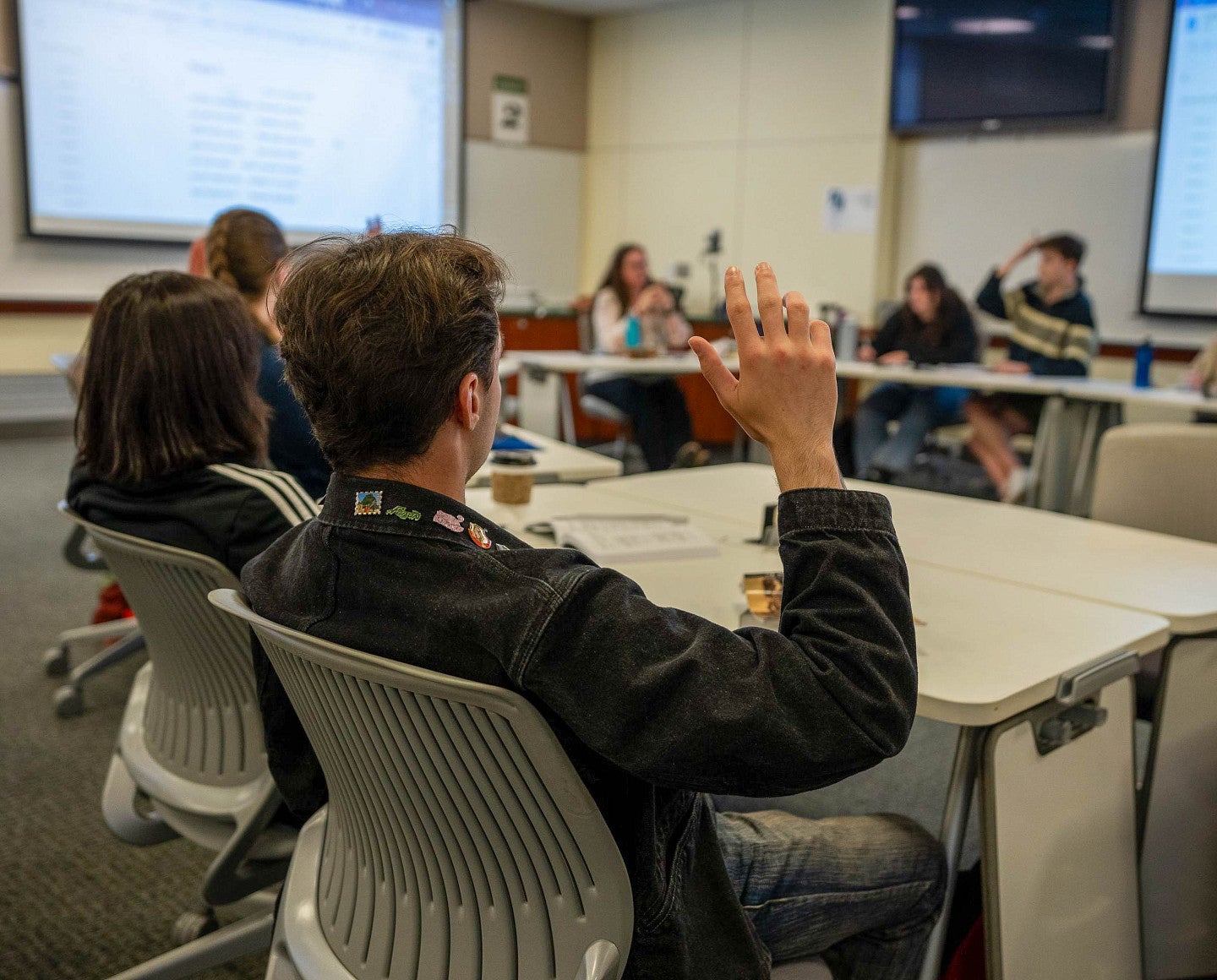 a person raises their hand in a small classroom setting