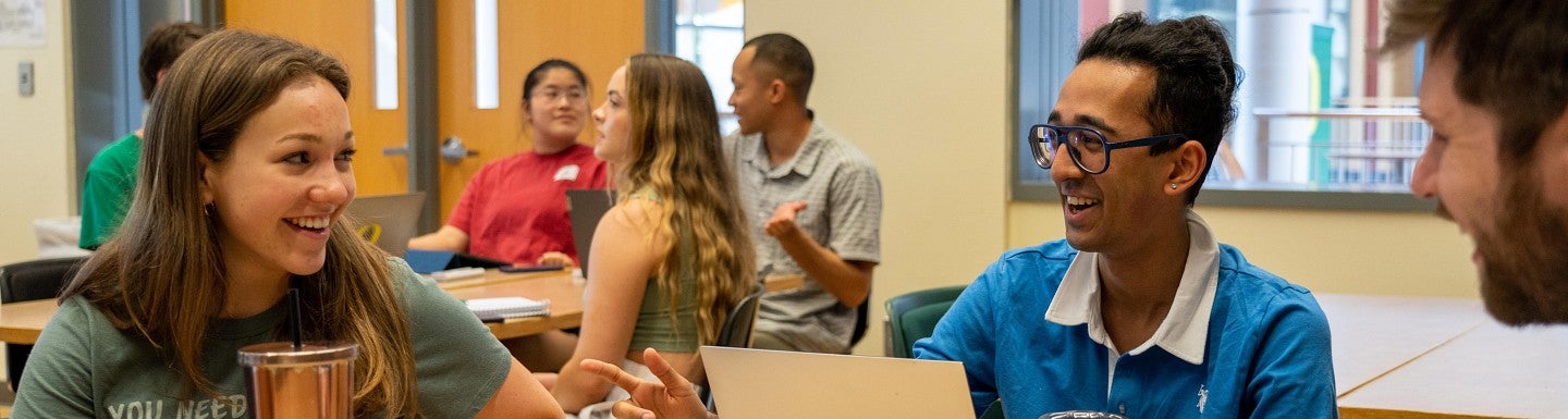 three people sitting in a classroom, talking