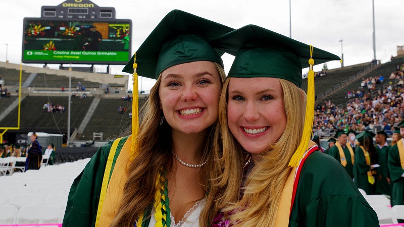 two graduates smiling at Autzen Stadium