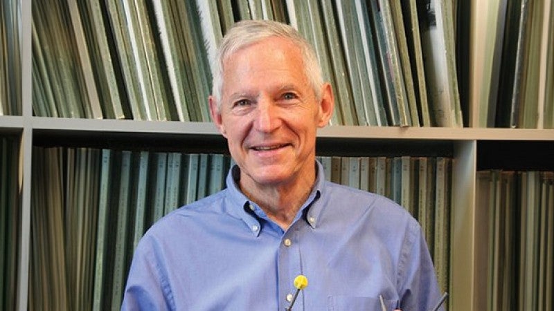 headshot of James E. Baldwin, standing in front of a bookshelf