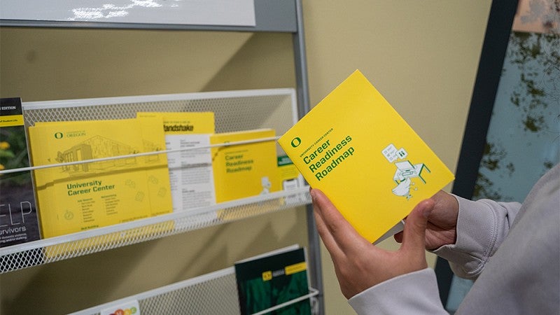 Person holding a yellow booklet with the title "Career Readiness Roadmap"