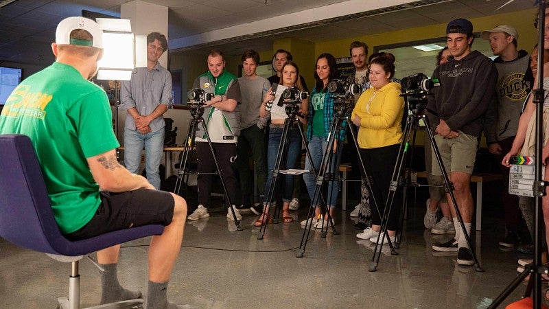 a group of students behind cameras with a person in front of a light