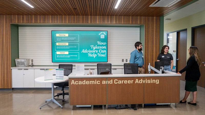 advisors chatting at the CAS Academic Advising desk on the first floor of Tykeson Hall