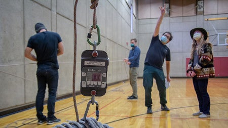 Physics Professor Graham Kribs calculates physical forces after testing force in an experiment with climbing equipment. 