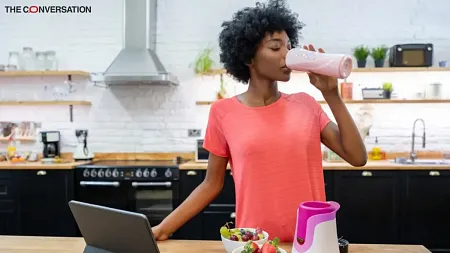 woman in kitchen drinking protein shake