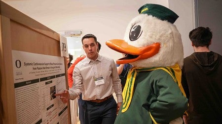 a student points to a poster being read by the Oregon Duck