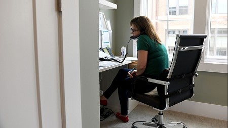 a woman sitting in an office chair, talking on the phone