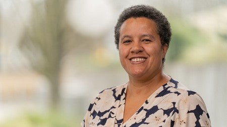 Philosophy professor Camisha Russell in floral shirt smiles at camera for professional head shot