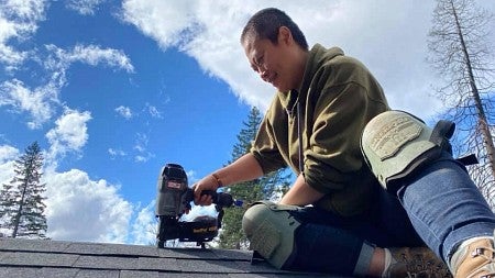 Person on a roof making repairs with a nail gun 