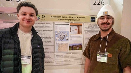 two students stand next to a research poster