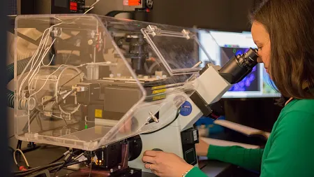 a woman looking through a microscope