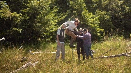 people standing in an open field surrounded by trees