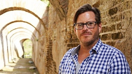 Associate Professor Kevin Dicus posing next to an ancient wall