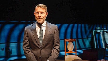 Chris Poulsen stands on a theatre stage