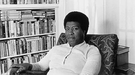 Octavia Butler sitting by a bookcase