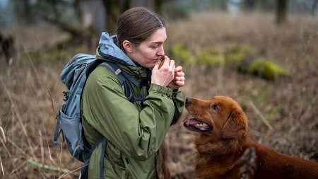 a woman smells a truffle while a dog watches