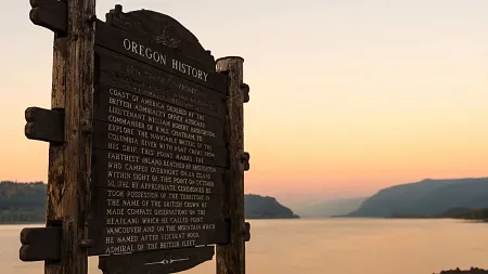 a wood sign in front of a setting sun