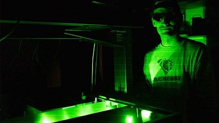 A student in lab wearing goggles illuminated by green laser